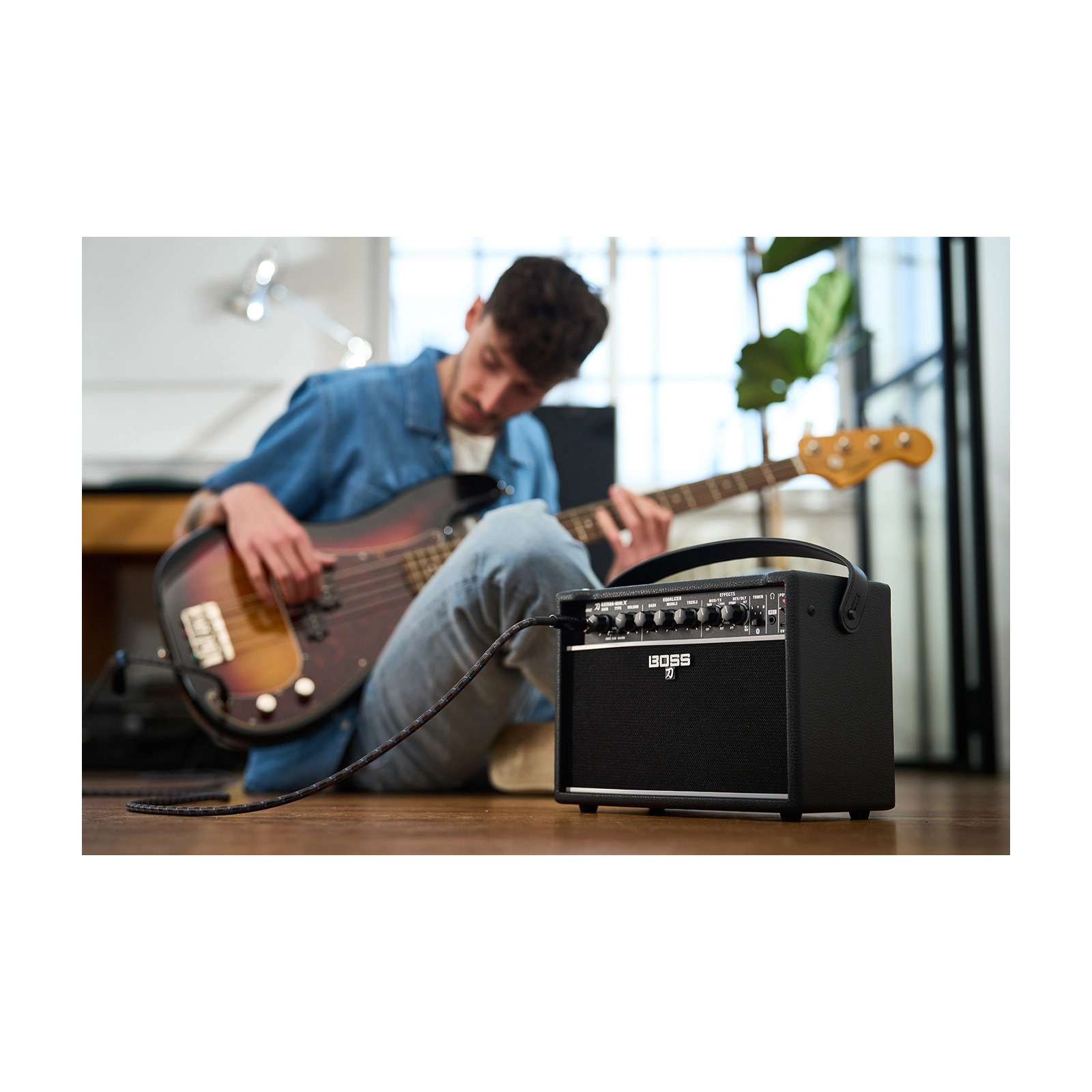 Person playing bass guitar with a Boss Katana Mini in a room.