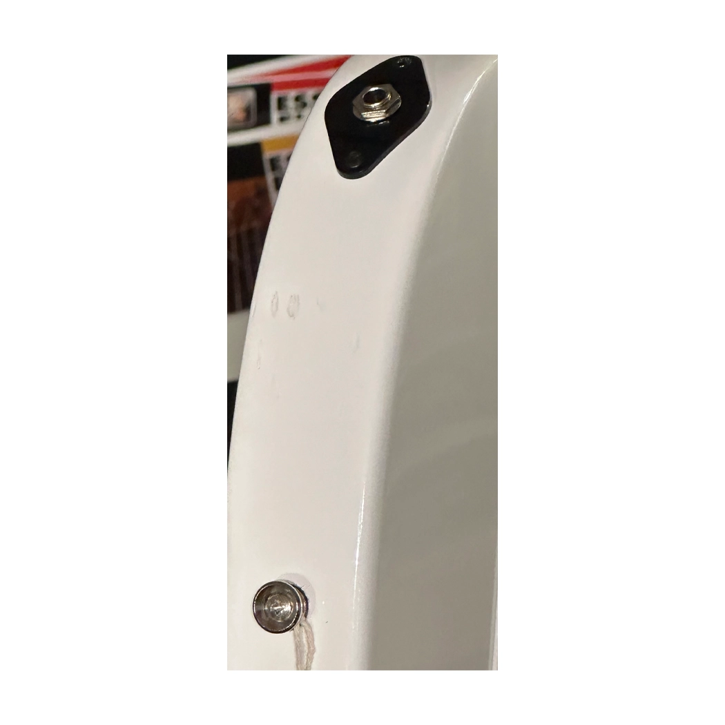 Close-up of a white vehicle's side panel with a black cover and visible bolts.