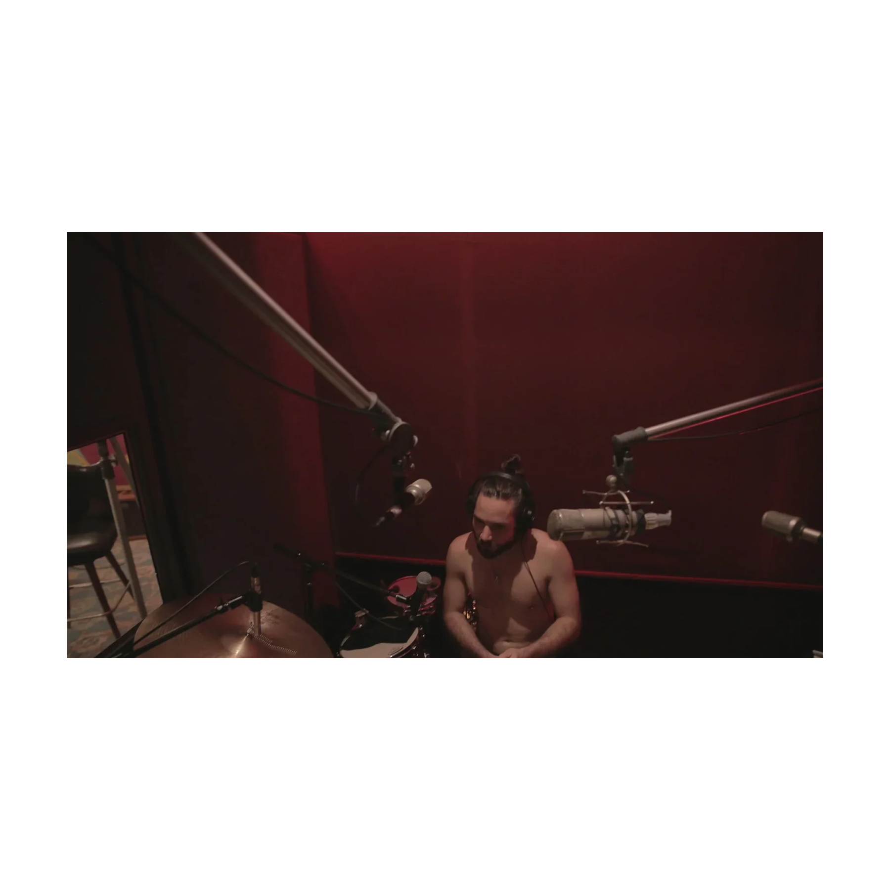 Person in a recording studio with microphones and equipment.