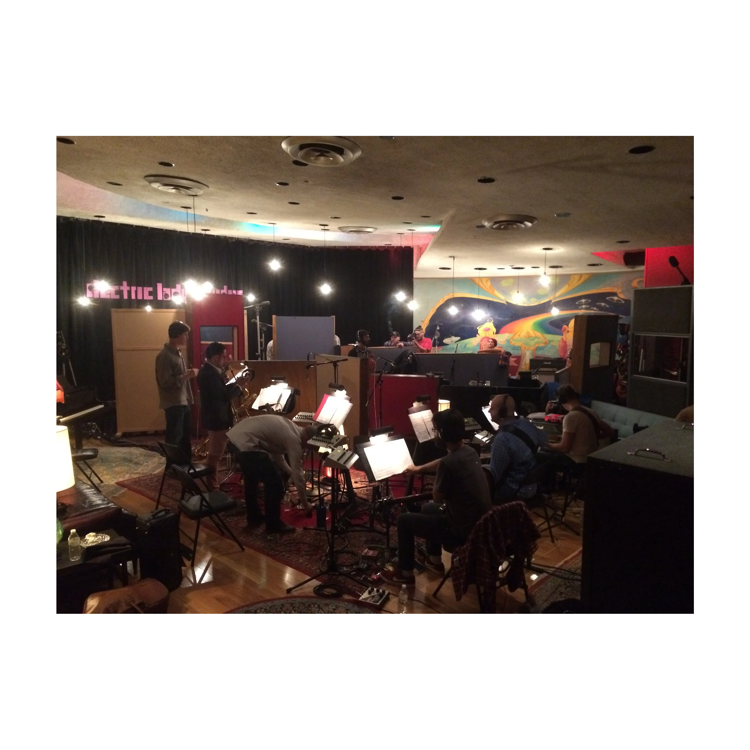 Studio with musicians and equipment, colorful mural on wall