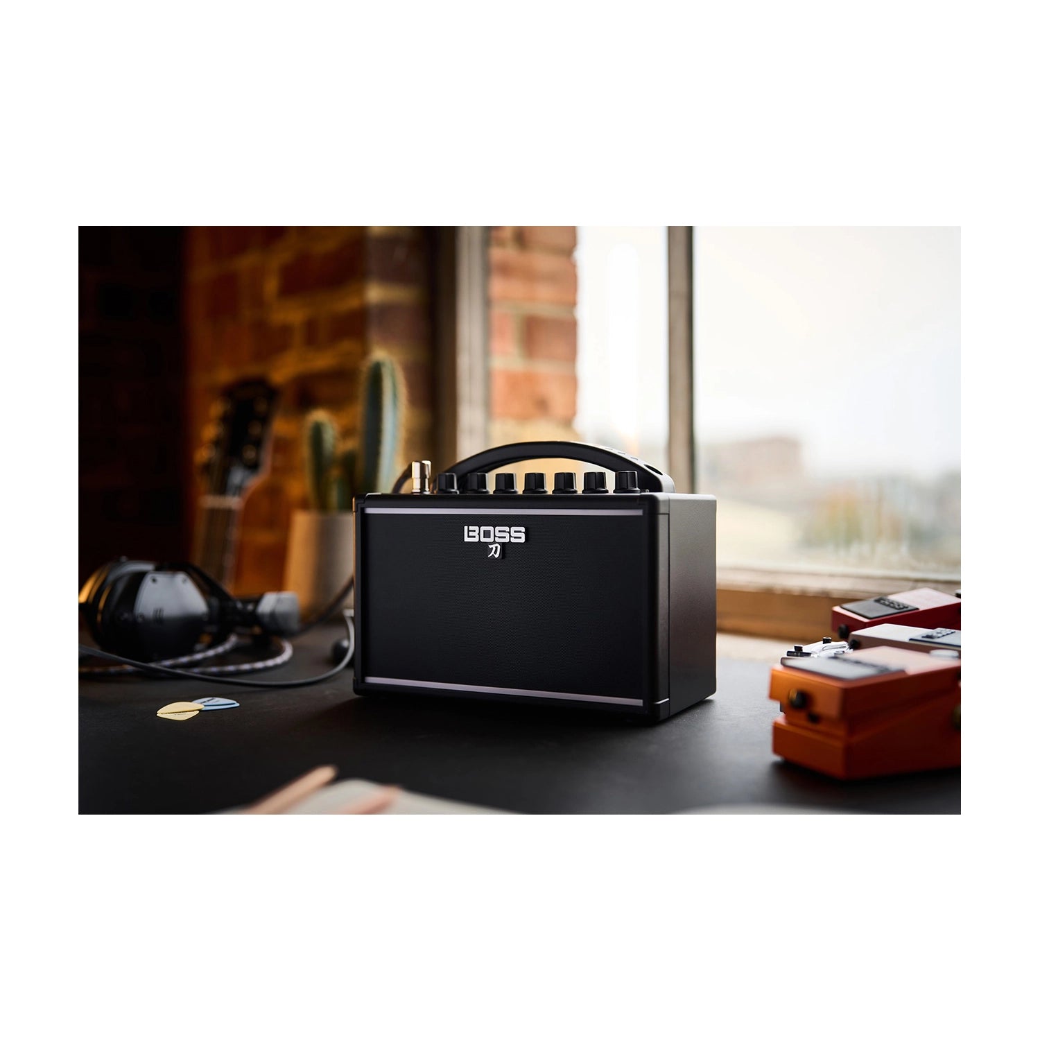 Boss Katana 7W Mini Guitar Amp on a desk with guitar pedals and headphones